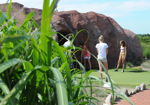Visitors playing Adventure Golf into a cave